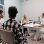 Doctors talking with patients during a medical appointment in a clinic office setting.