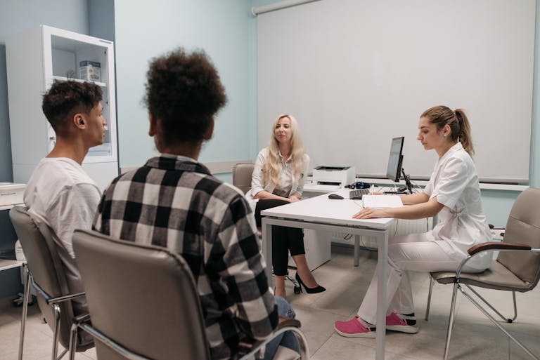 Doctors talking with patients during a medical appointment in a clinic office setting.